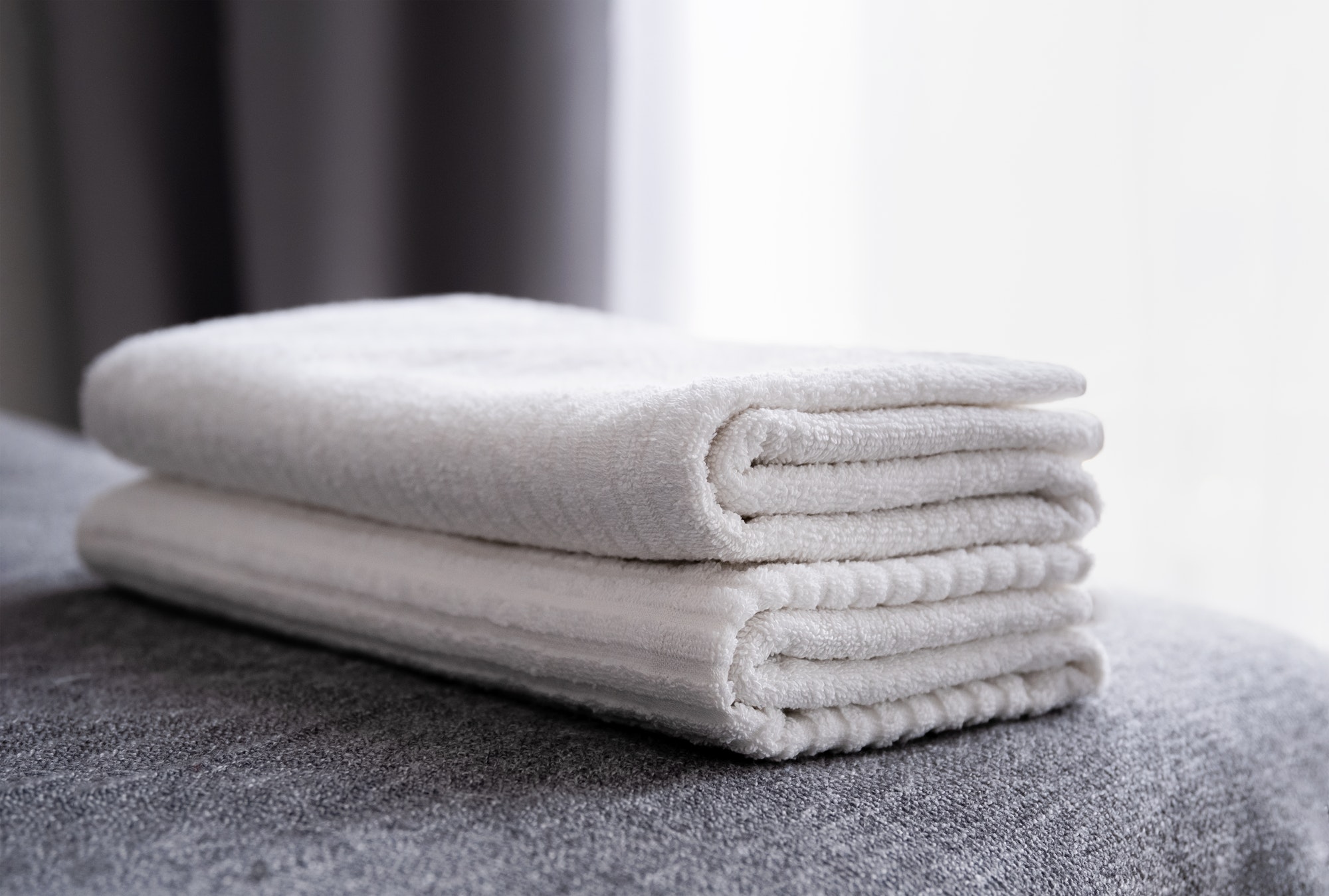 Hotel staff, fresh white bath towels on the bed.